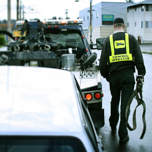 A tow truck driver carrying a towing strap to a tow truck